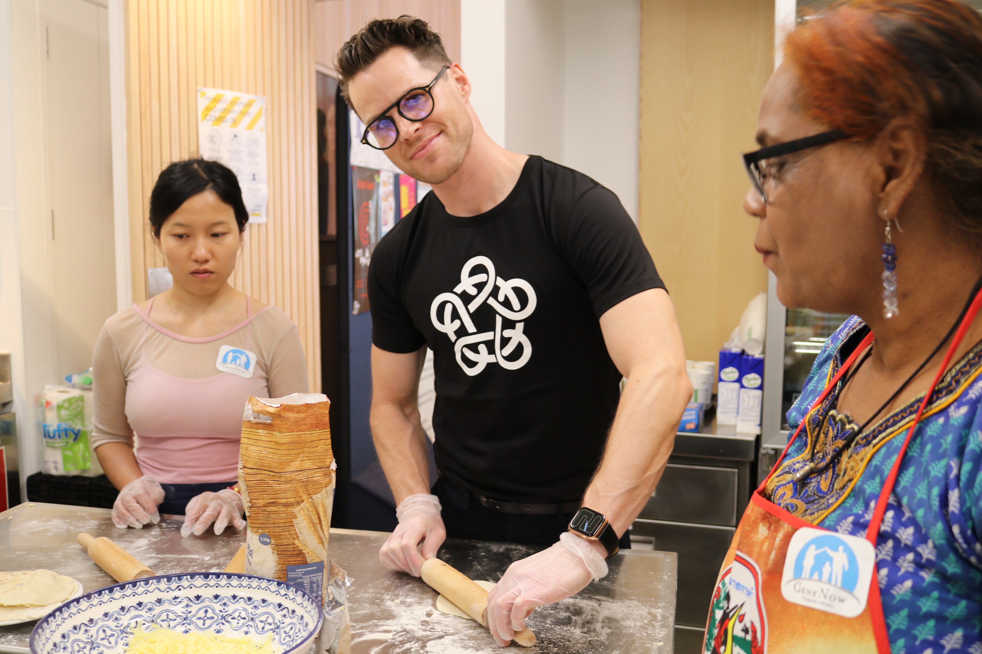 Lee smiling at camera rolling dough