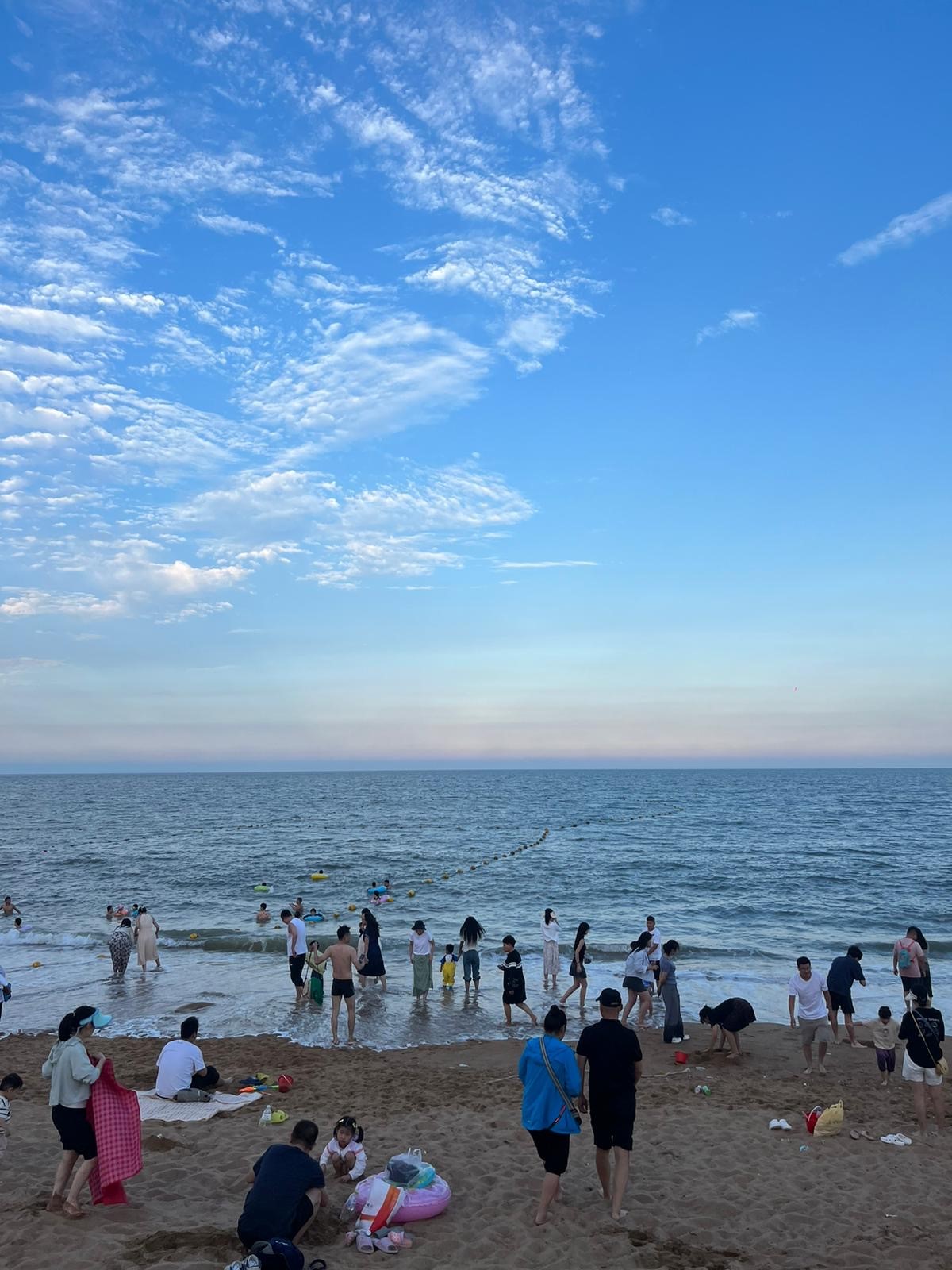 A crowded shot of people at the edge of the water on a beach