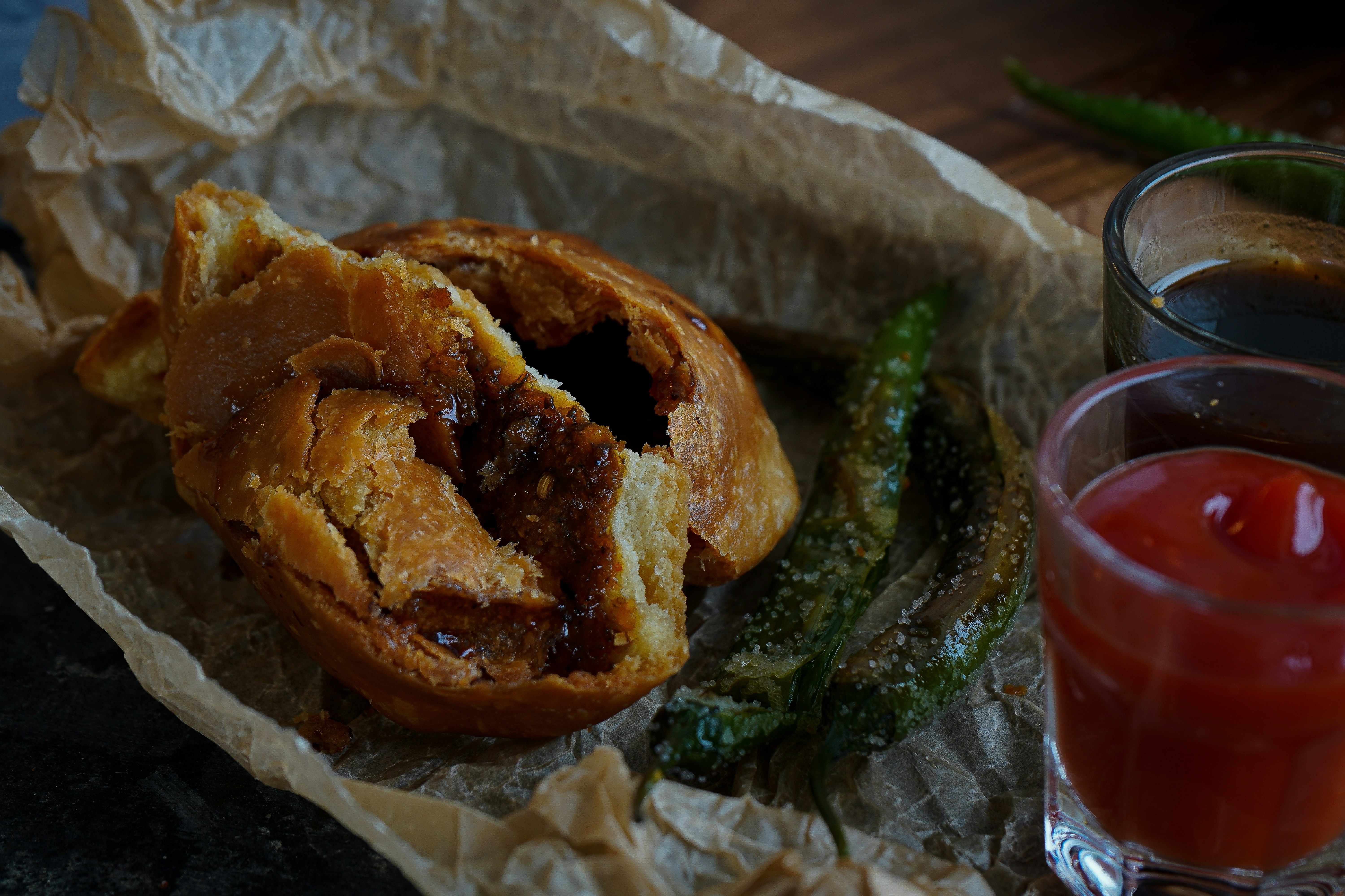 A crispy bread-like pastry sits in a container with a dipping sauce