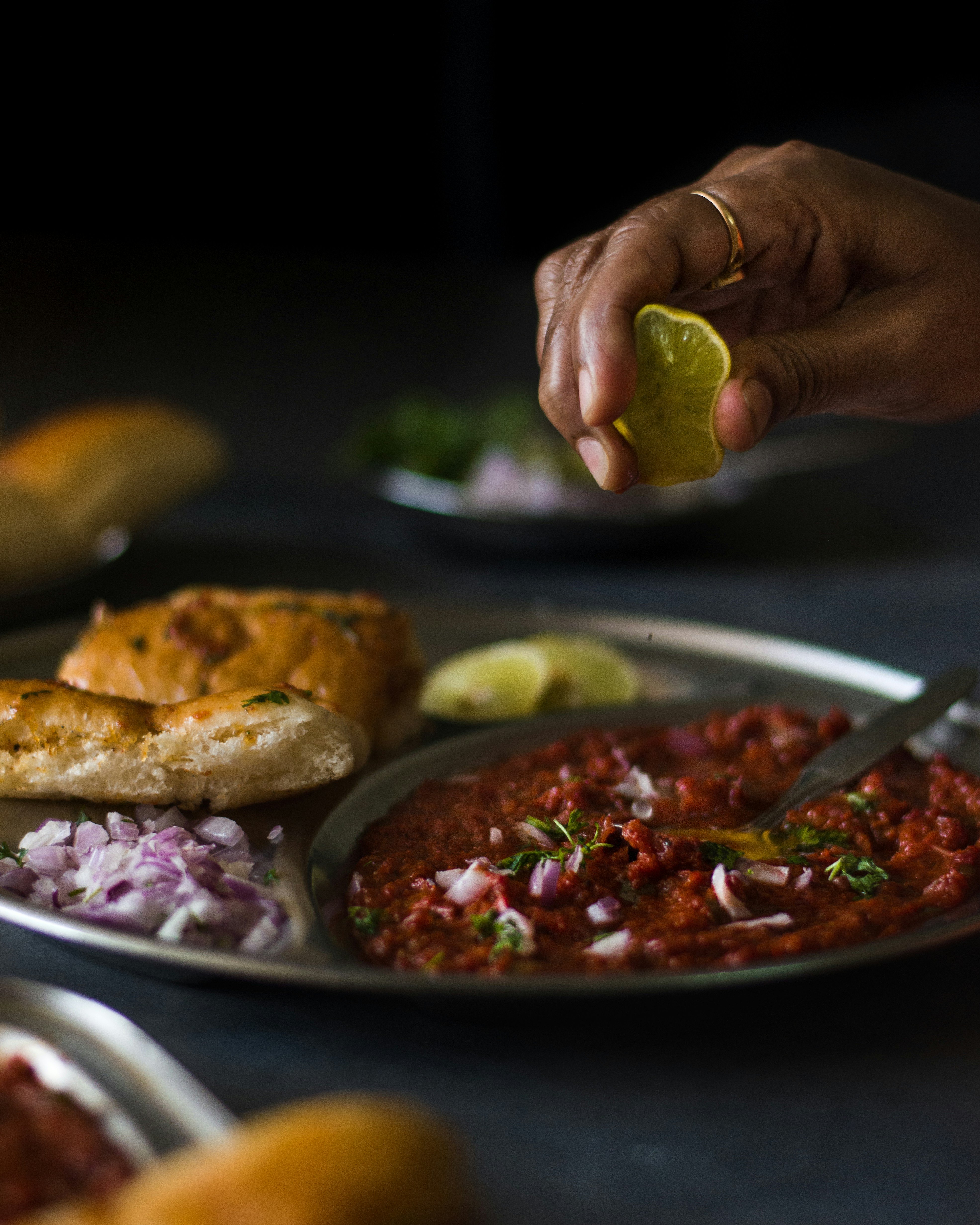 A wedge of lime is being squeezed over a plate with food