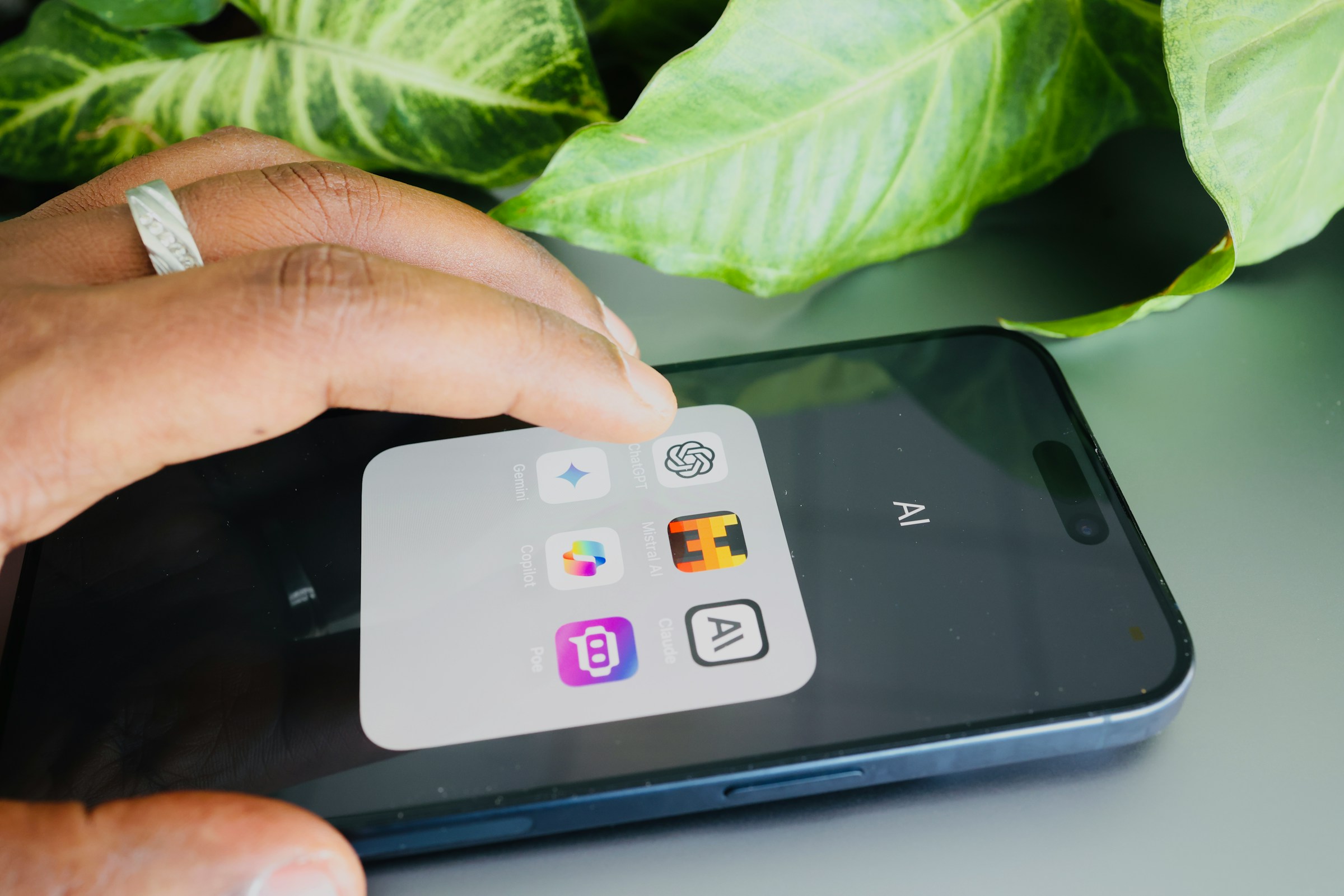 A hand hovers over a smartphone showing tiles for AI applications