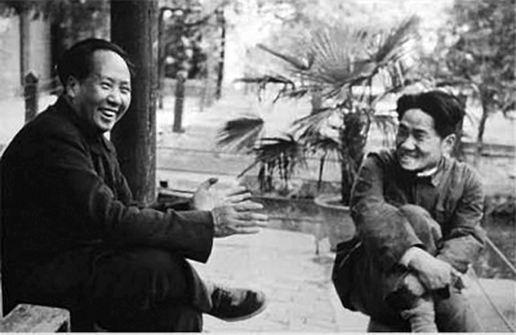 A black and white photo of a smiling Mao Zedong sitting on a bench across from his son Mao Anying