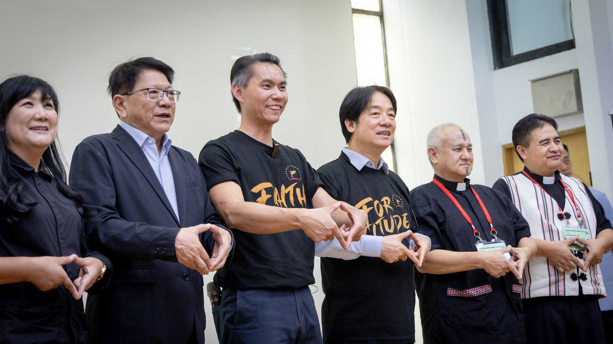 Six people stand in a row, each making a triangle gesture with their hands