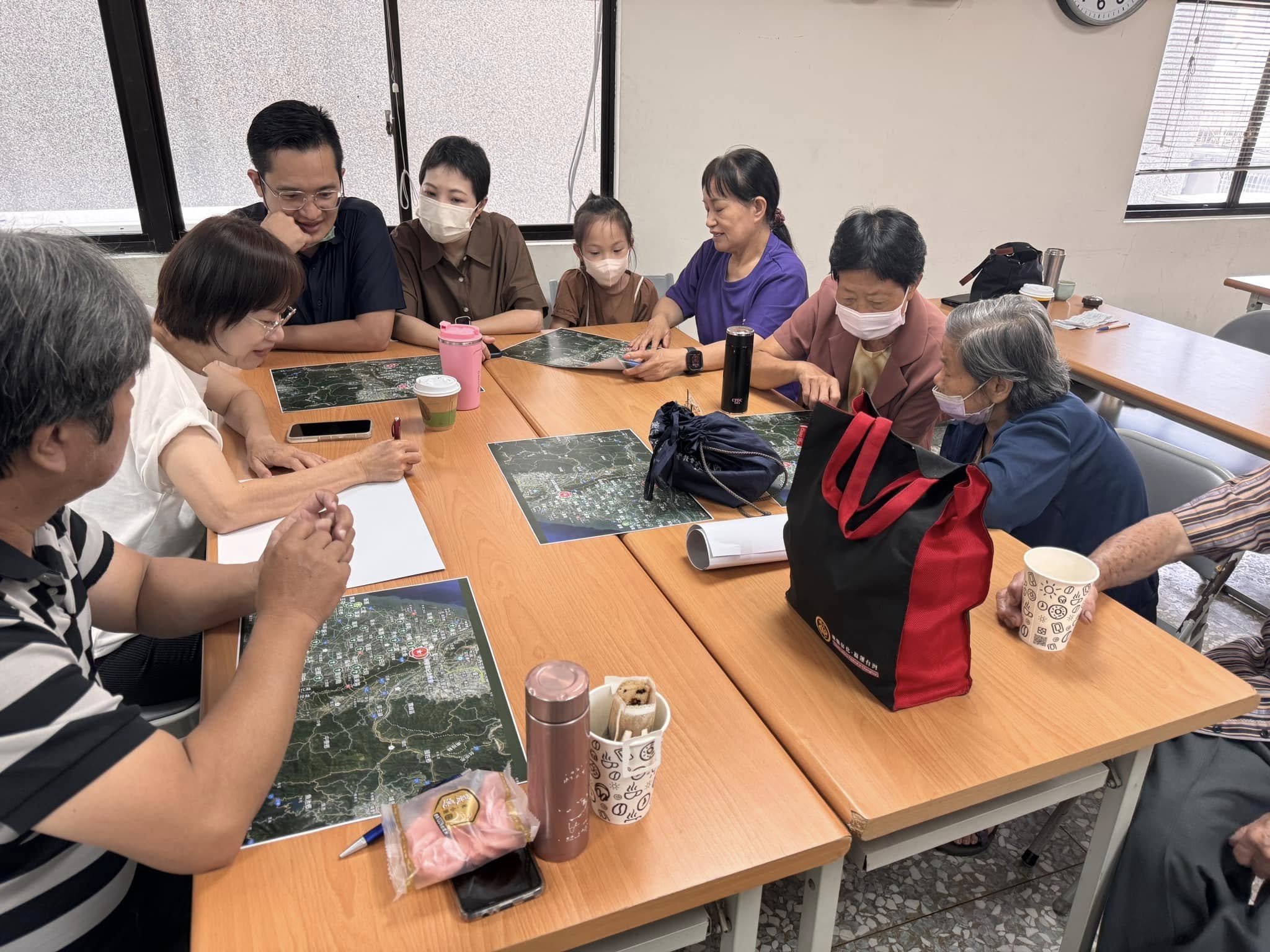 A group of people sit around a table, poring over maps