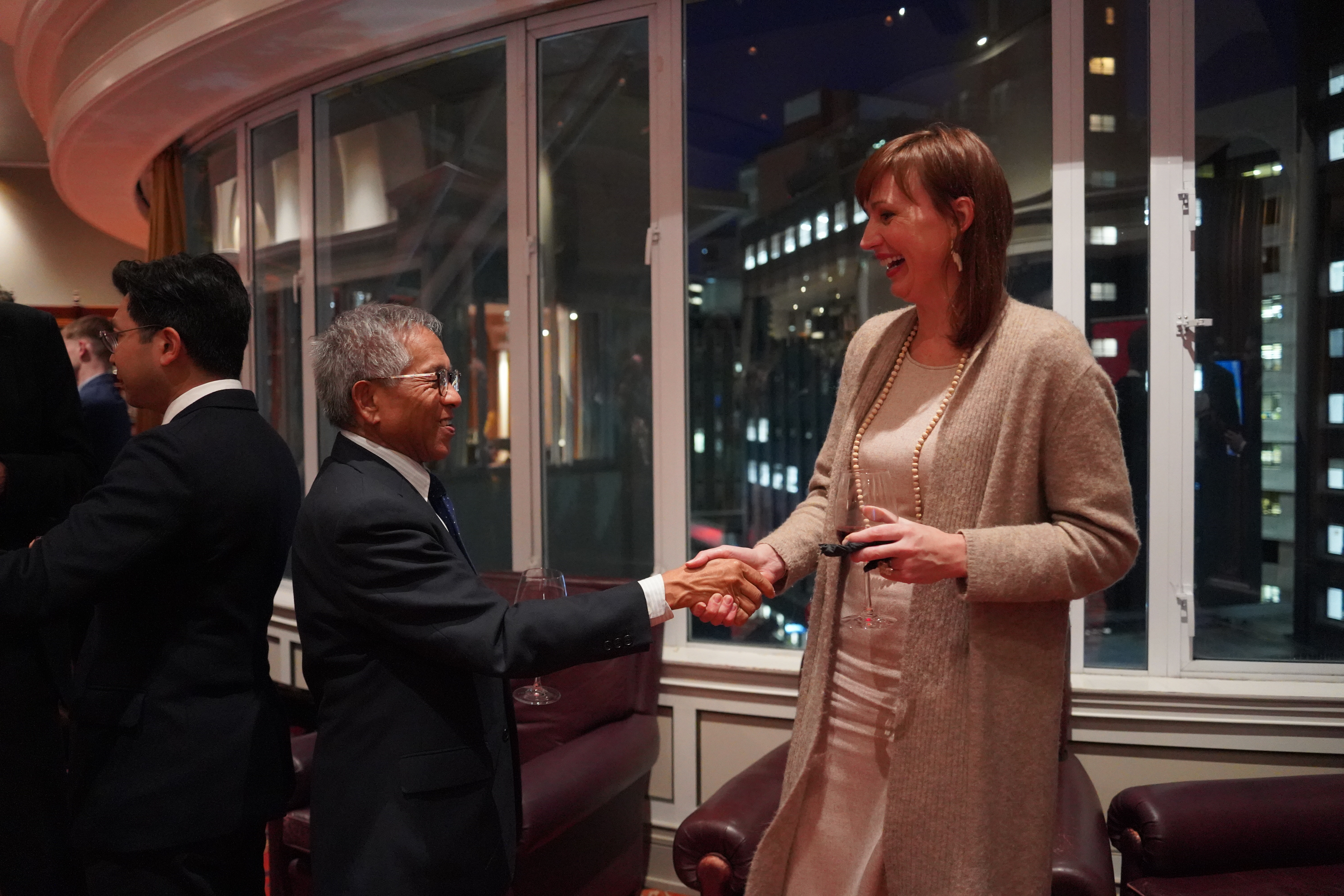 A man and a woman shake hands while looking at each other and laughing