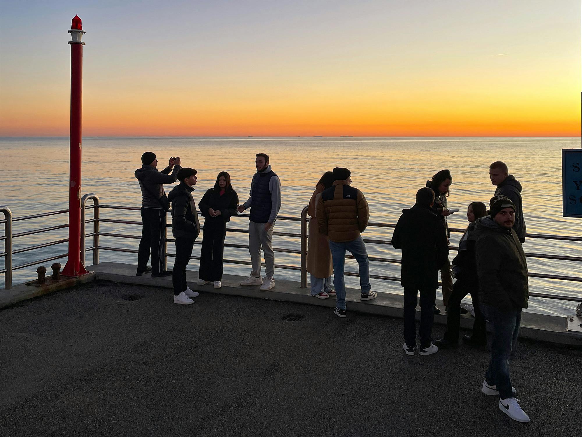 Ragazzi al tramonto in inverno sul pontile di Forte dei Marmi
