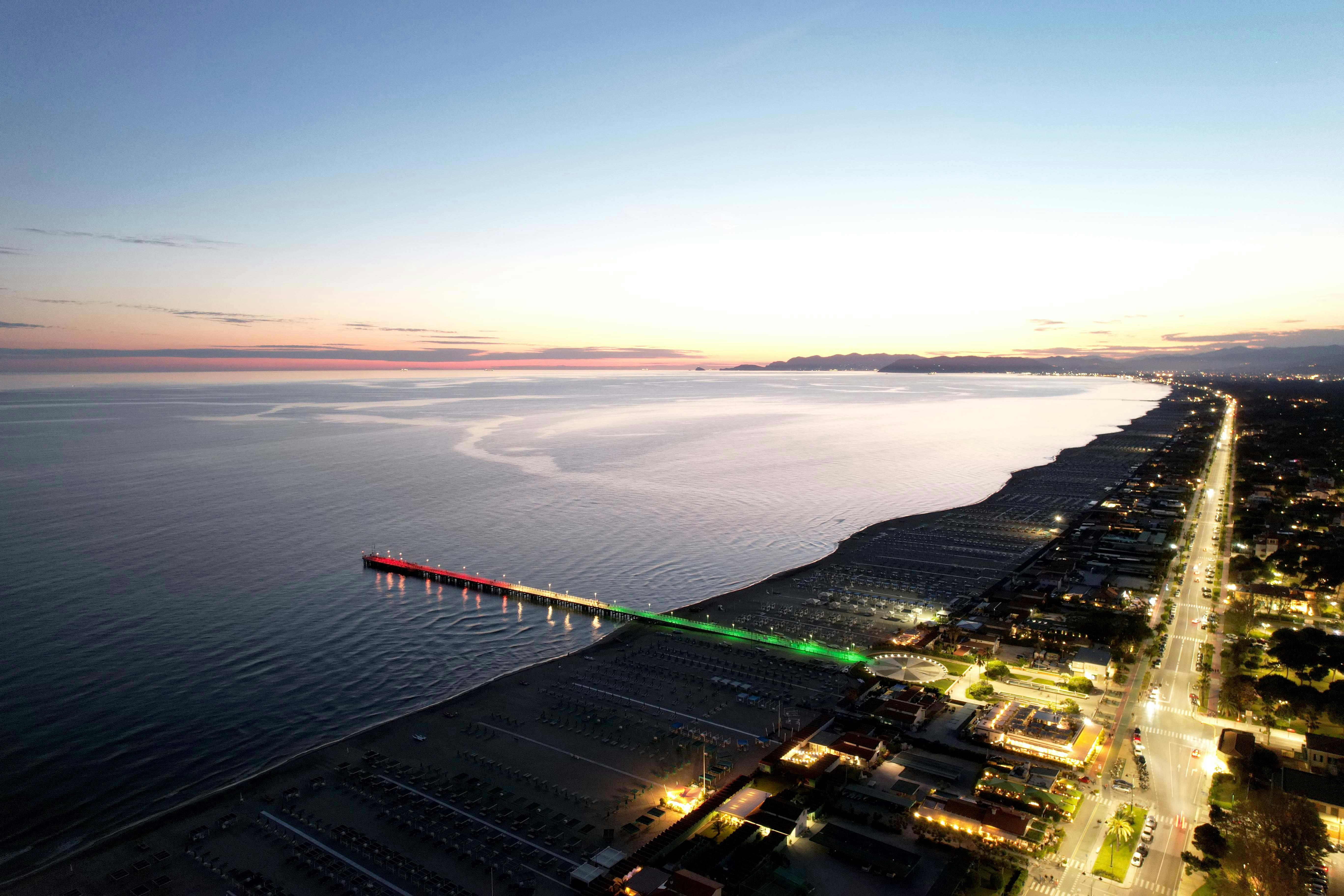 Una suggestiva veduta del pontile di Forte dei Marmi illuminato con il tricolore della bandiera italiana