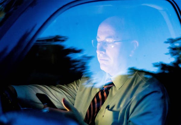 Man looking down at phone while driving