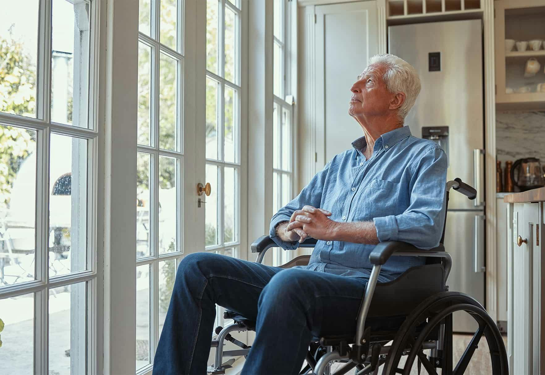 Older man sitting in a wheelchair looking out the window