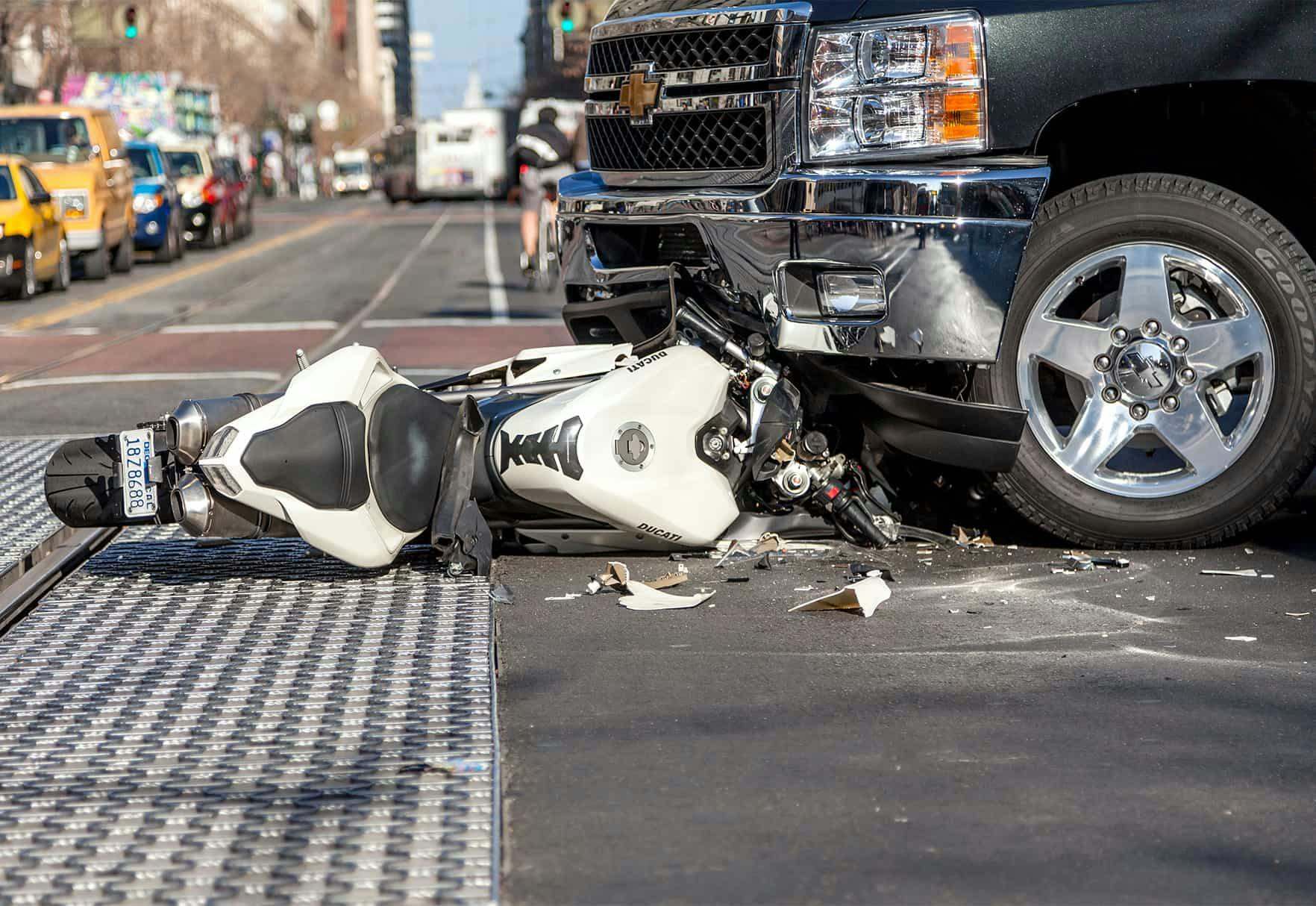 A wrecked bike under a truck