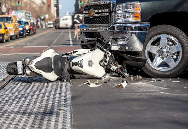 A wrecked bike under a truck