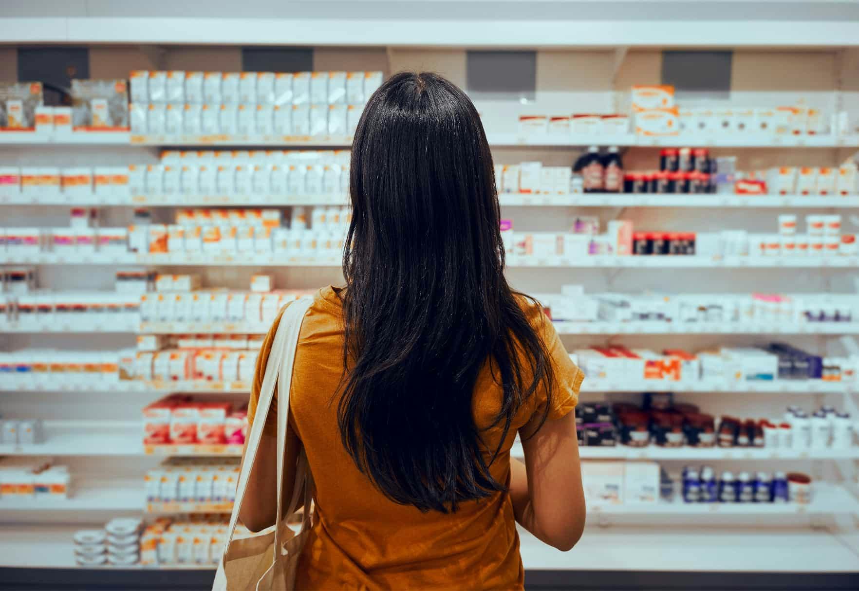 A woman in front of a medication store shelf