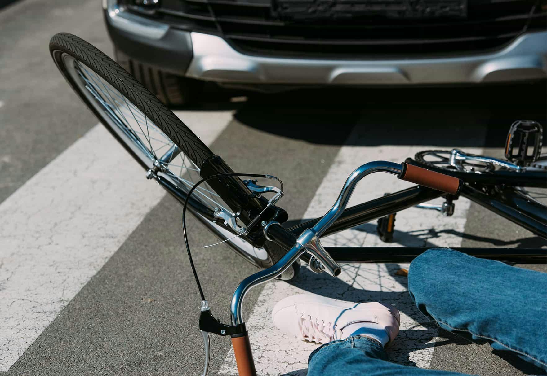 A bicycle rider on the ground after being hit by a car