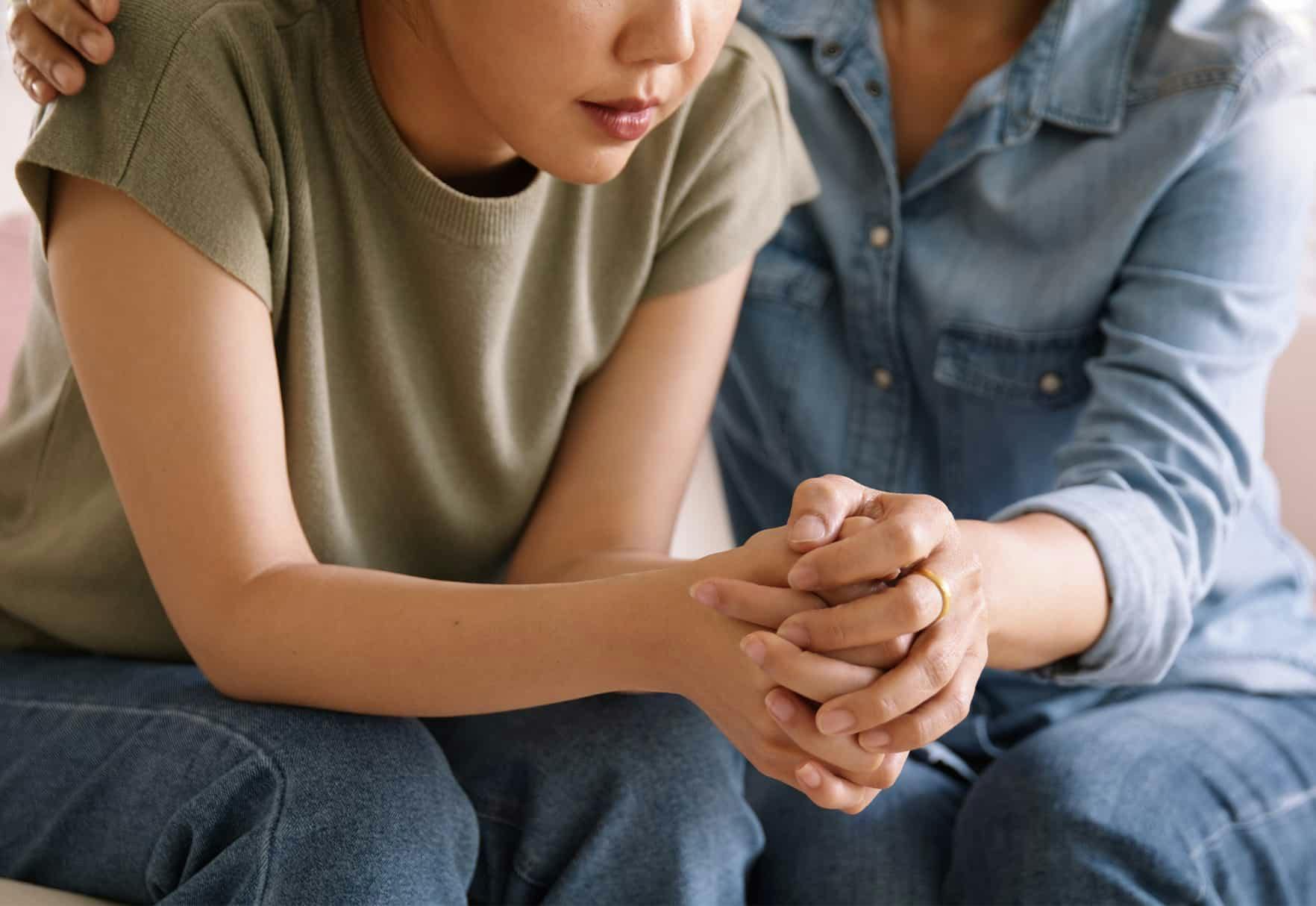 People holding hands while grieving