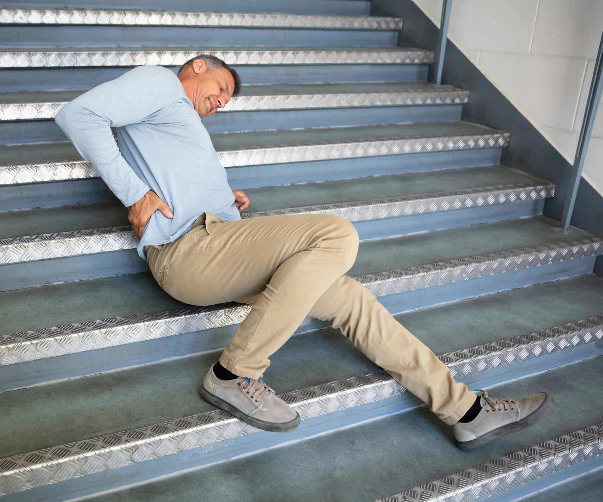 A man on stairs holding back in pain