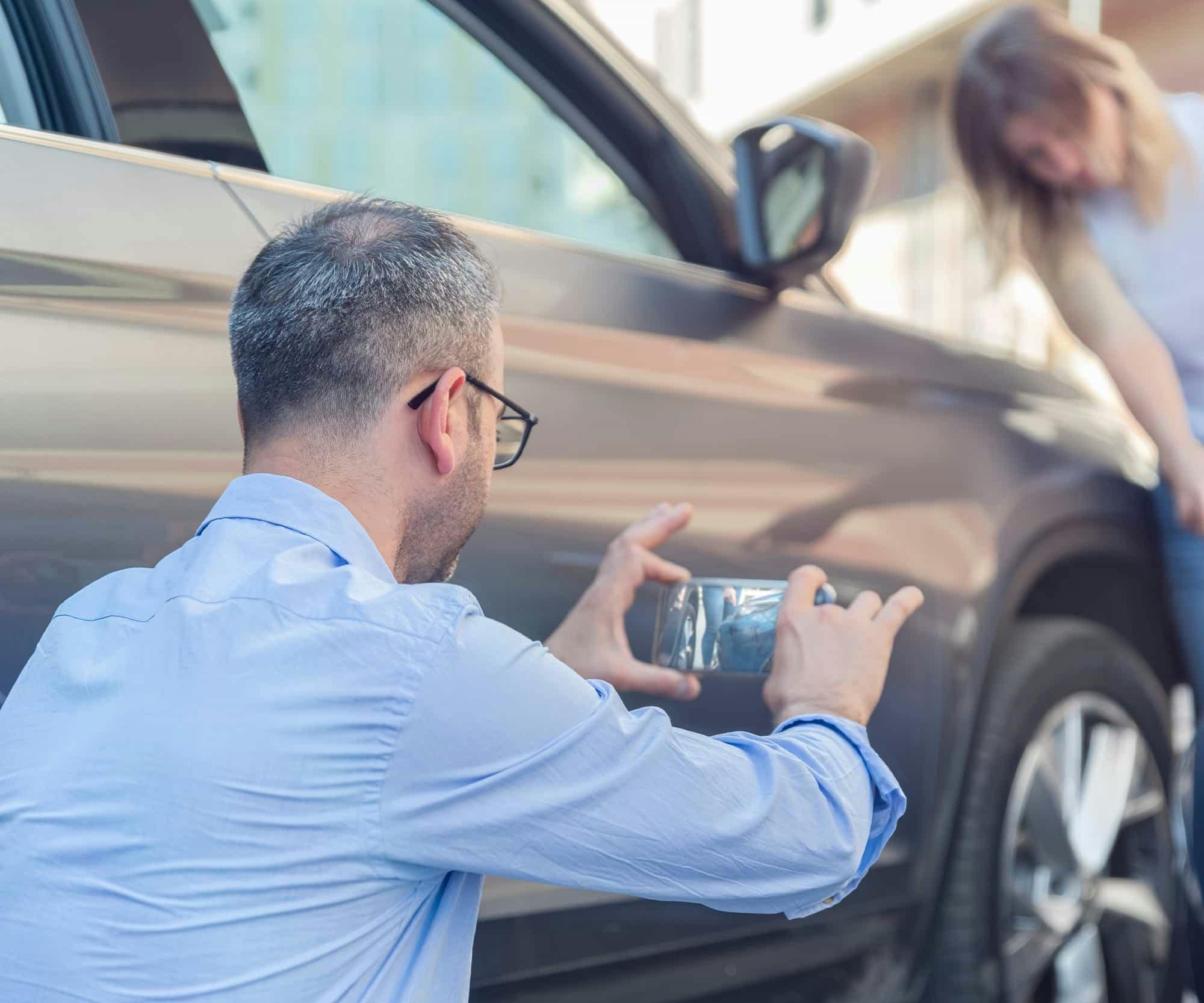 man taking a picture of the damages after an accident