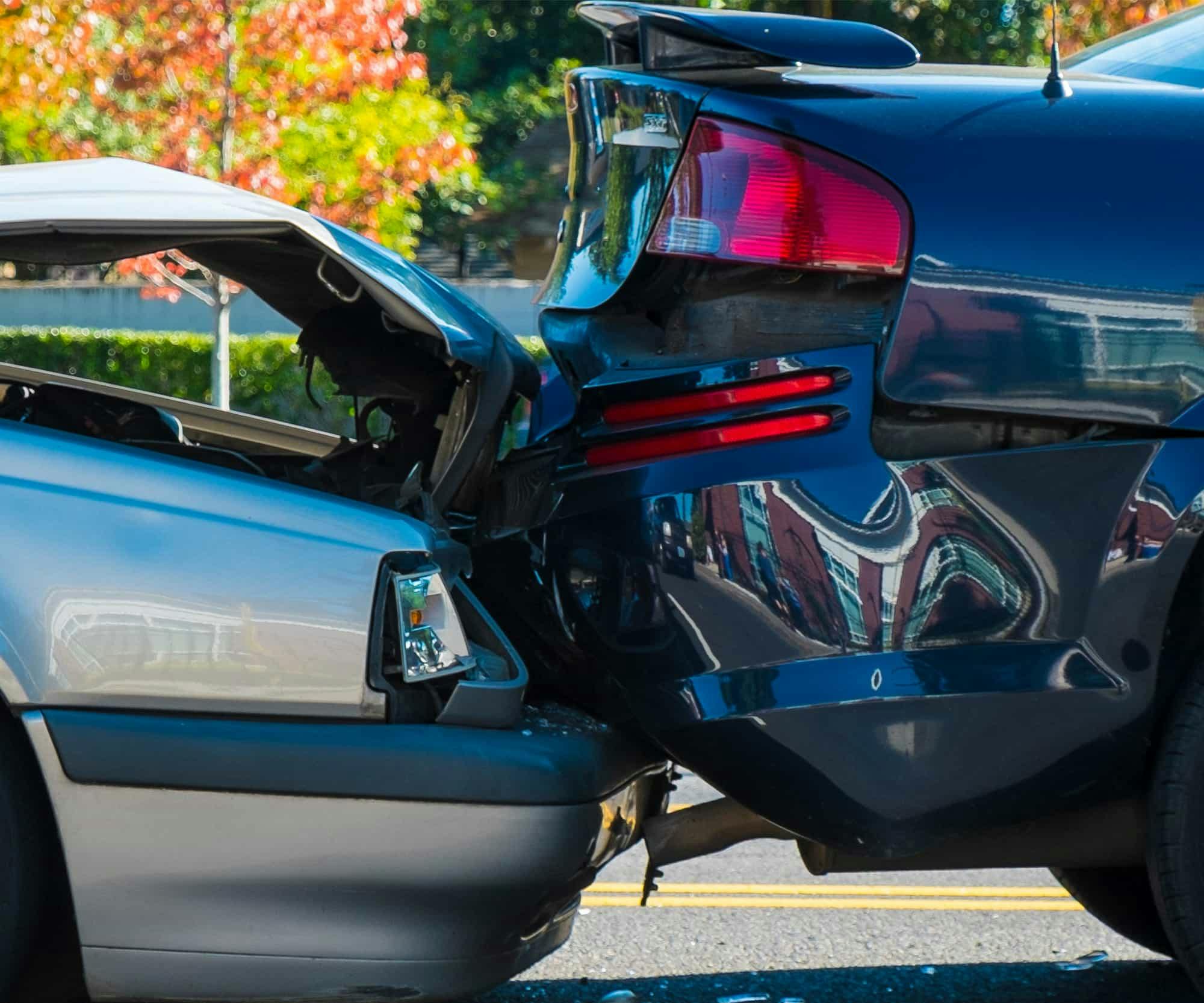 A silver car rear-ending a black car