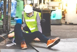 A workplace injury with a man in a safety vest laying down.