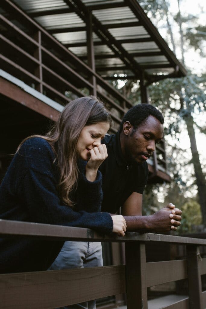A man and a woman crying leaning over fence