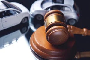 2 toy cars and a gavel to signify the importance of working with an accident attorney to pursue damages from a car insurance company.