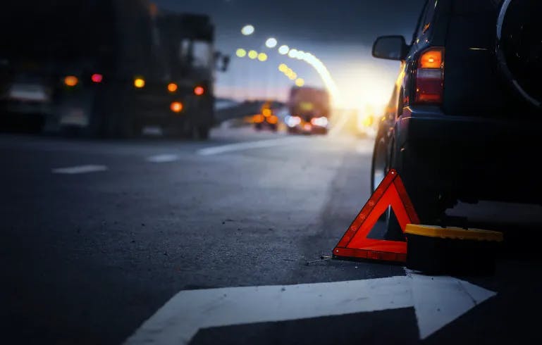 A car with a traffic cone behind it after being in an accident.