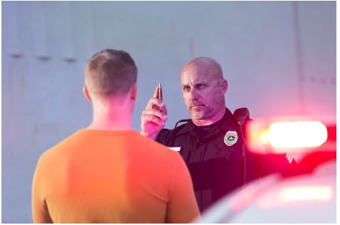 A police officer doing a DUI check on a man.