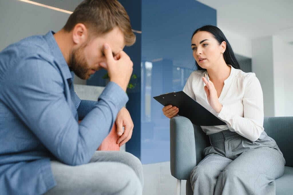 An upset man speaking with a therapist.