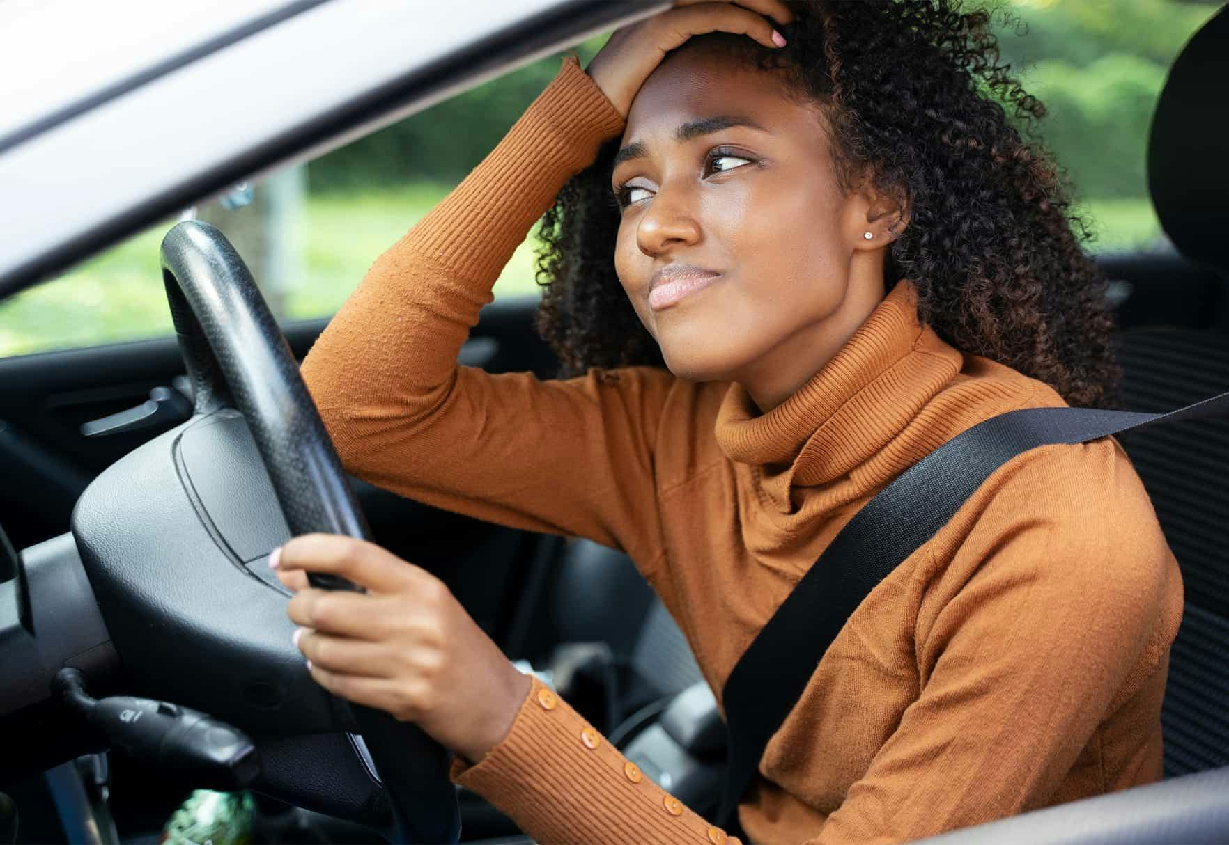 Woman holding her head while sitting in the car