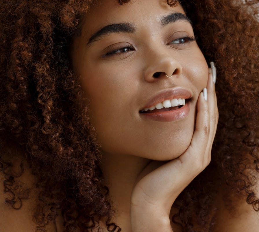 woman with curly hair resting her face on her hand