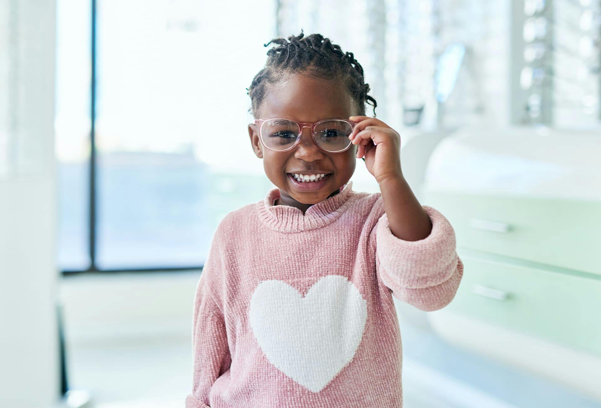 toddler fixing her glasses and smilling