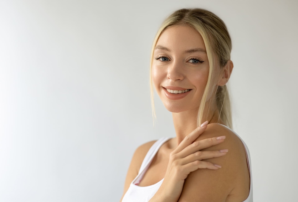 woman with ponytail smiling with hand on her shoulder