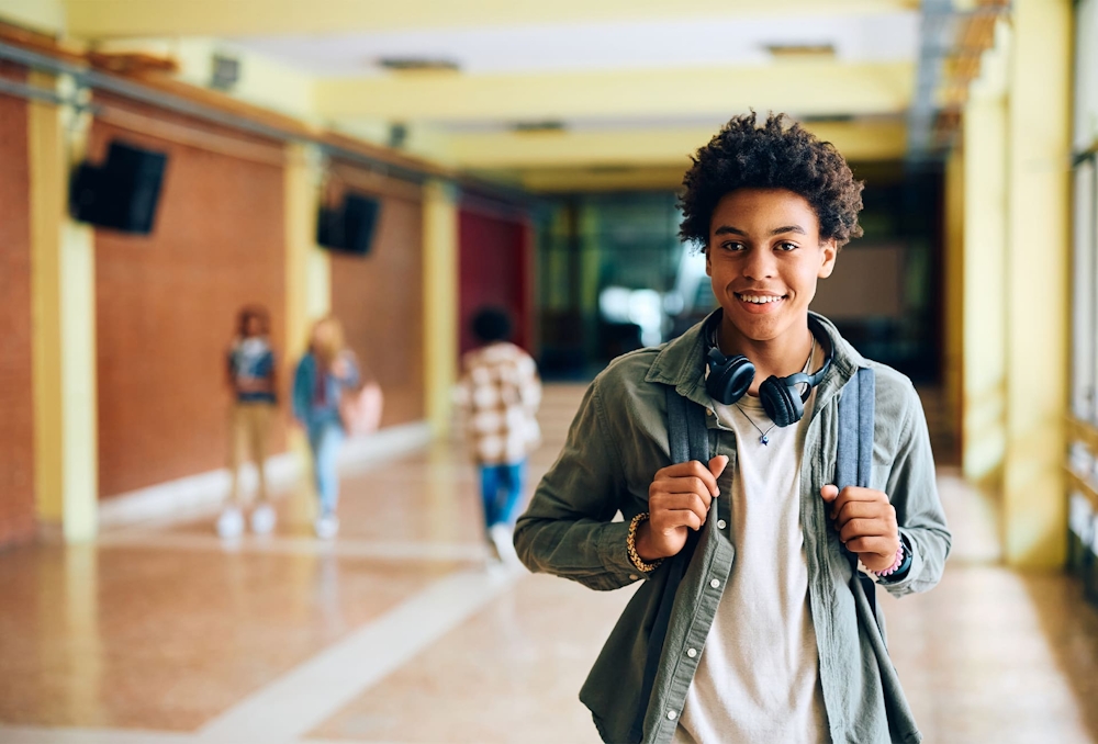 teenager in school holding backpack straps