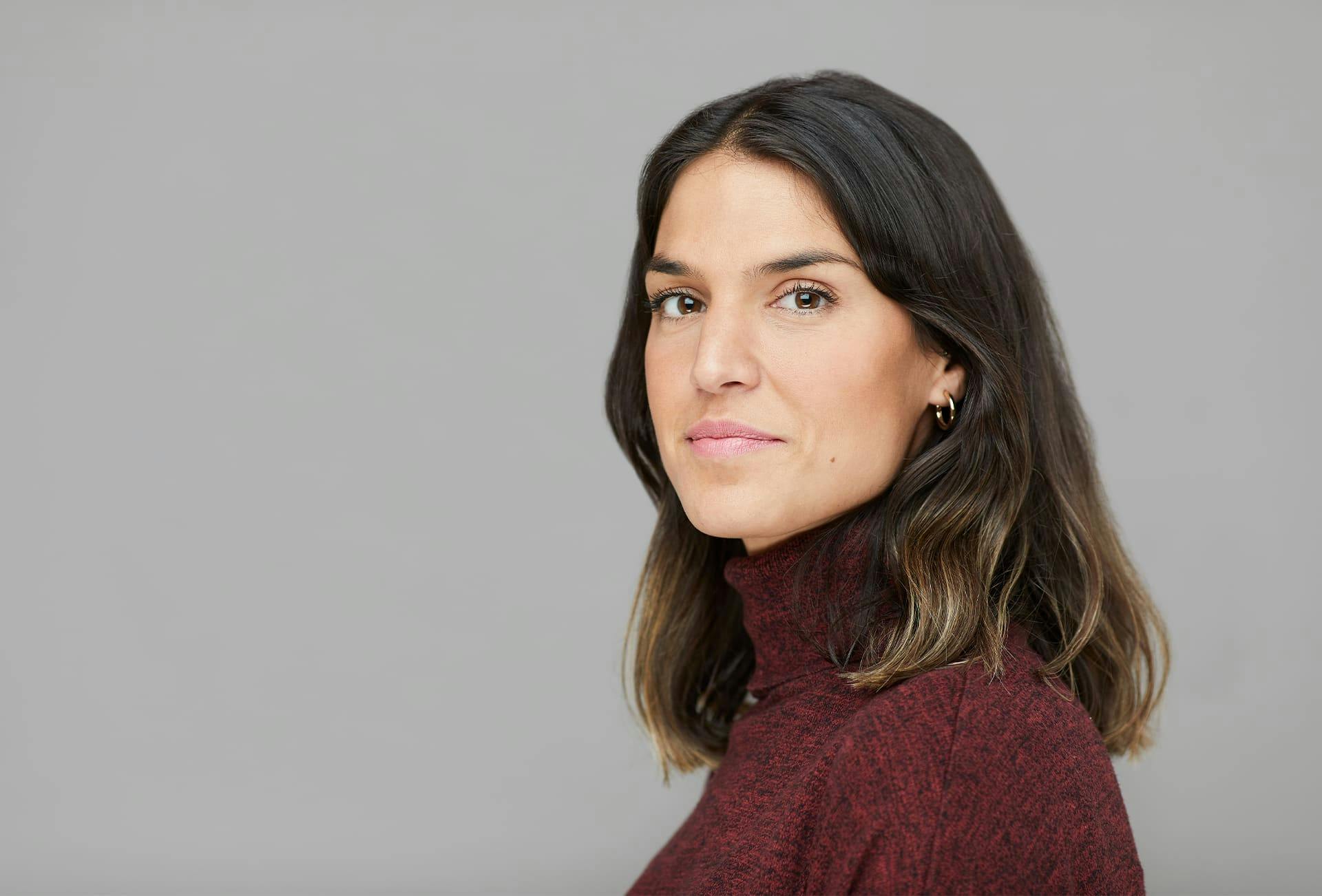 woman in red turtleneck standing sideways looking forward