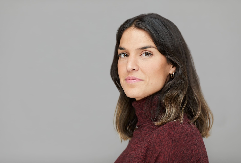 woman in red turtleneck standing sideways looking forward