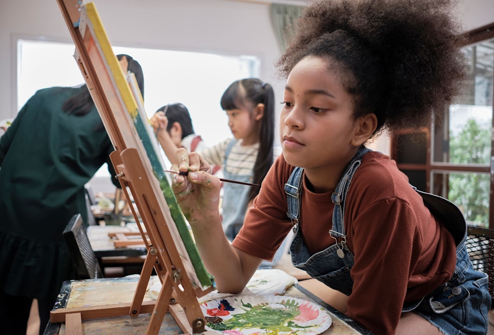 young girl painting on an easel