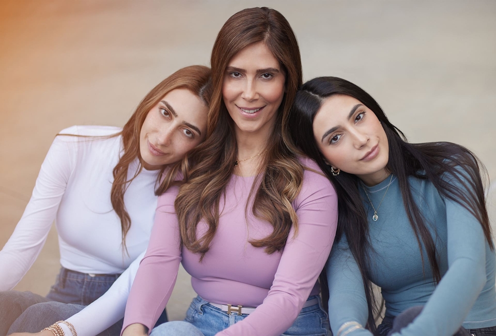 3 woman sitting together with 2 putting their heads on the middle woman's shoulders