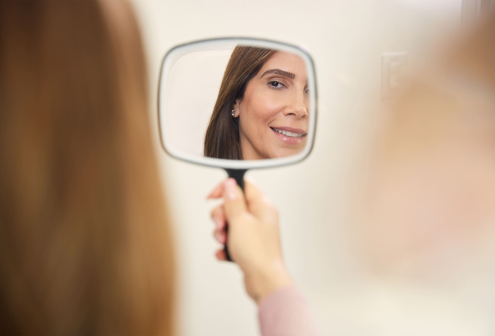 patient smiling into handheld mirror