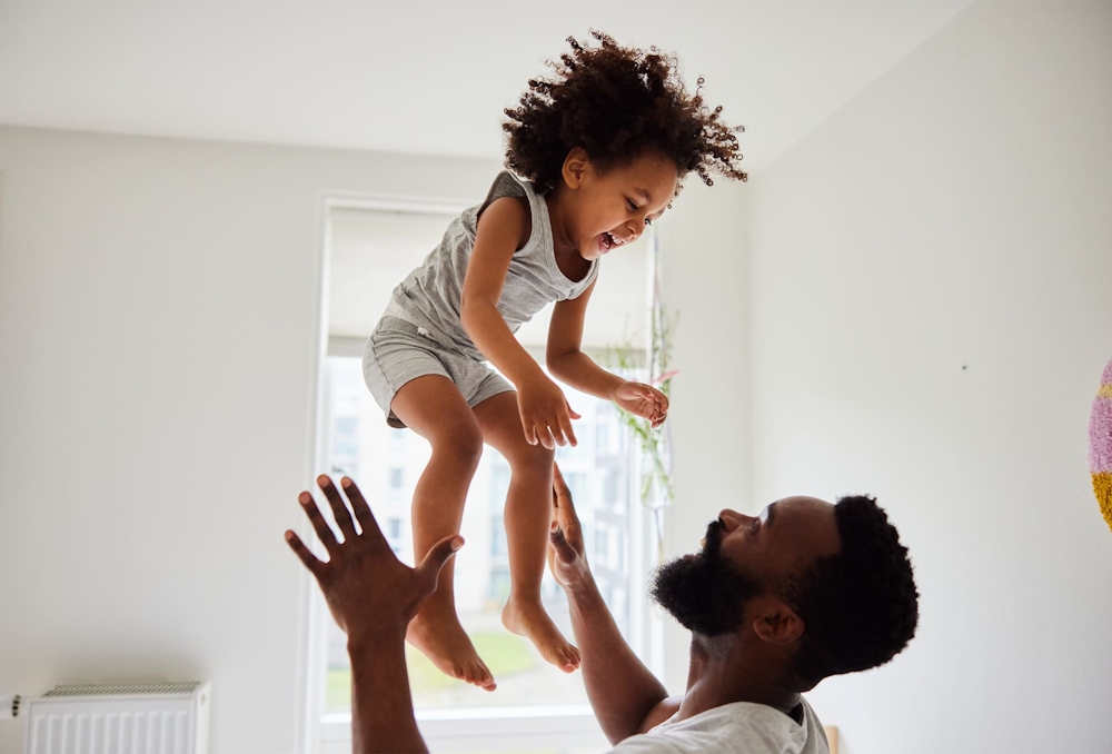 man throwing toddler up in air while toddler smiles
