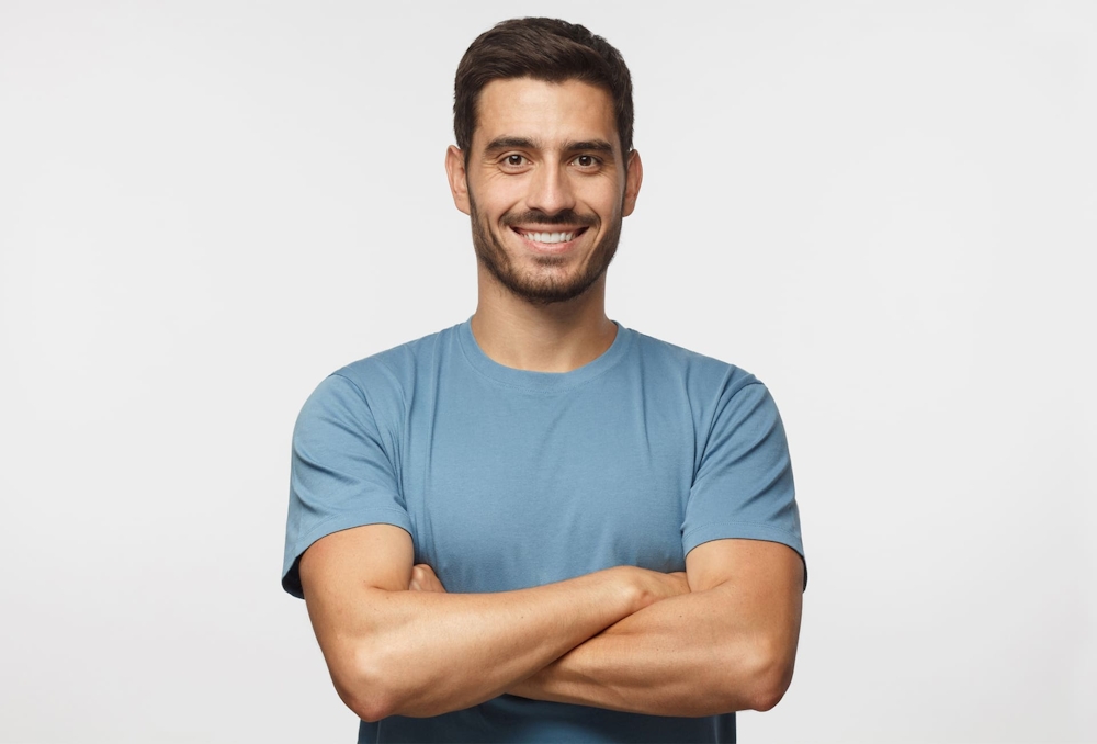 man crossing arms and smiling in blue shirt