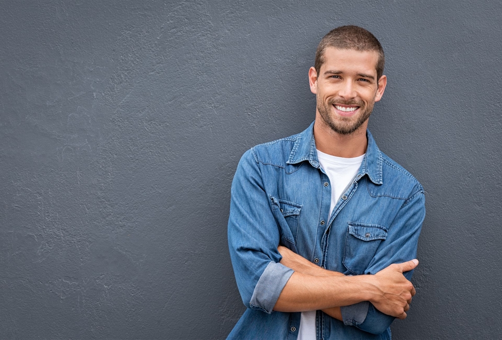 man in jean jacket crossing his arms and smiling