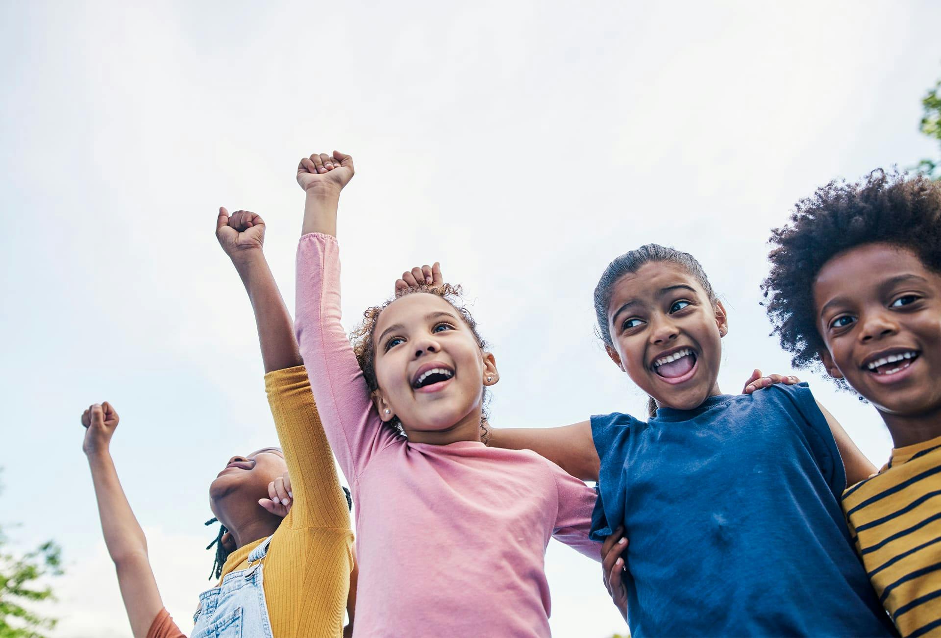 kids raising their hands up hugging eachother