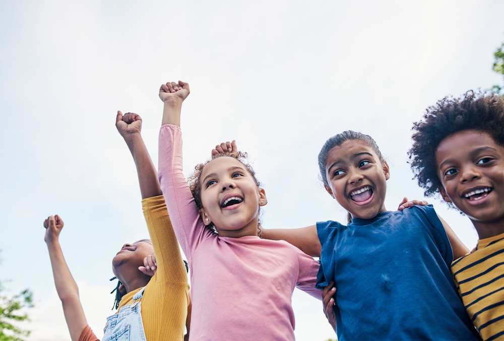 kids raising their hands up hugging eachother