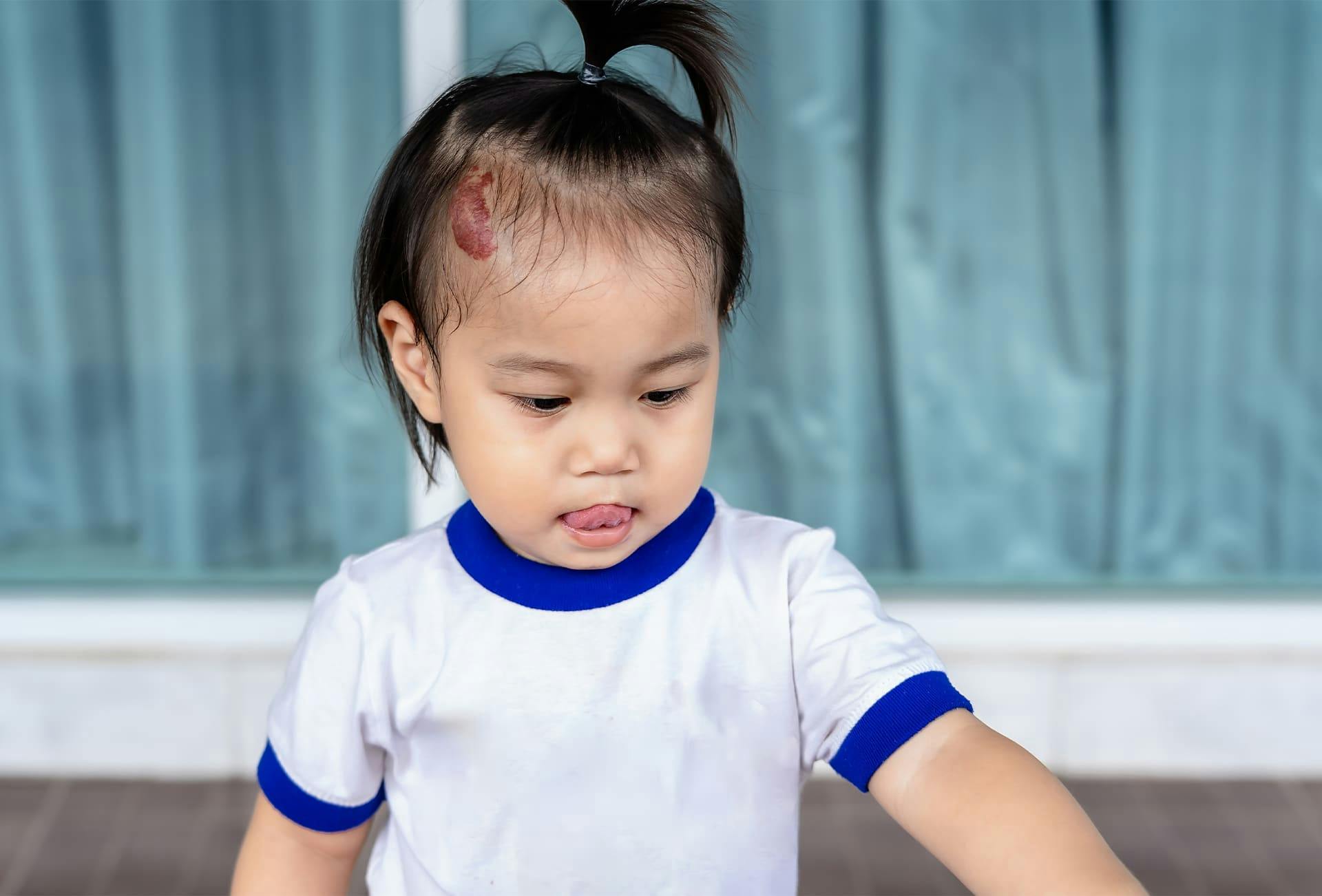 child wearing a white shirt with their hair in a ponytail