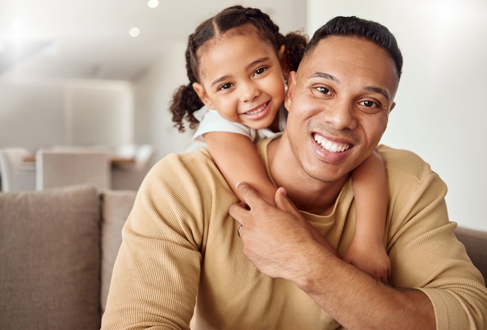toddler hugging her father from behind