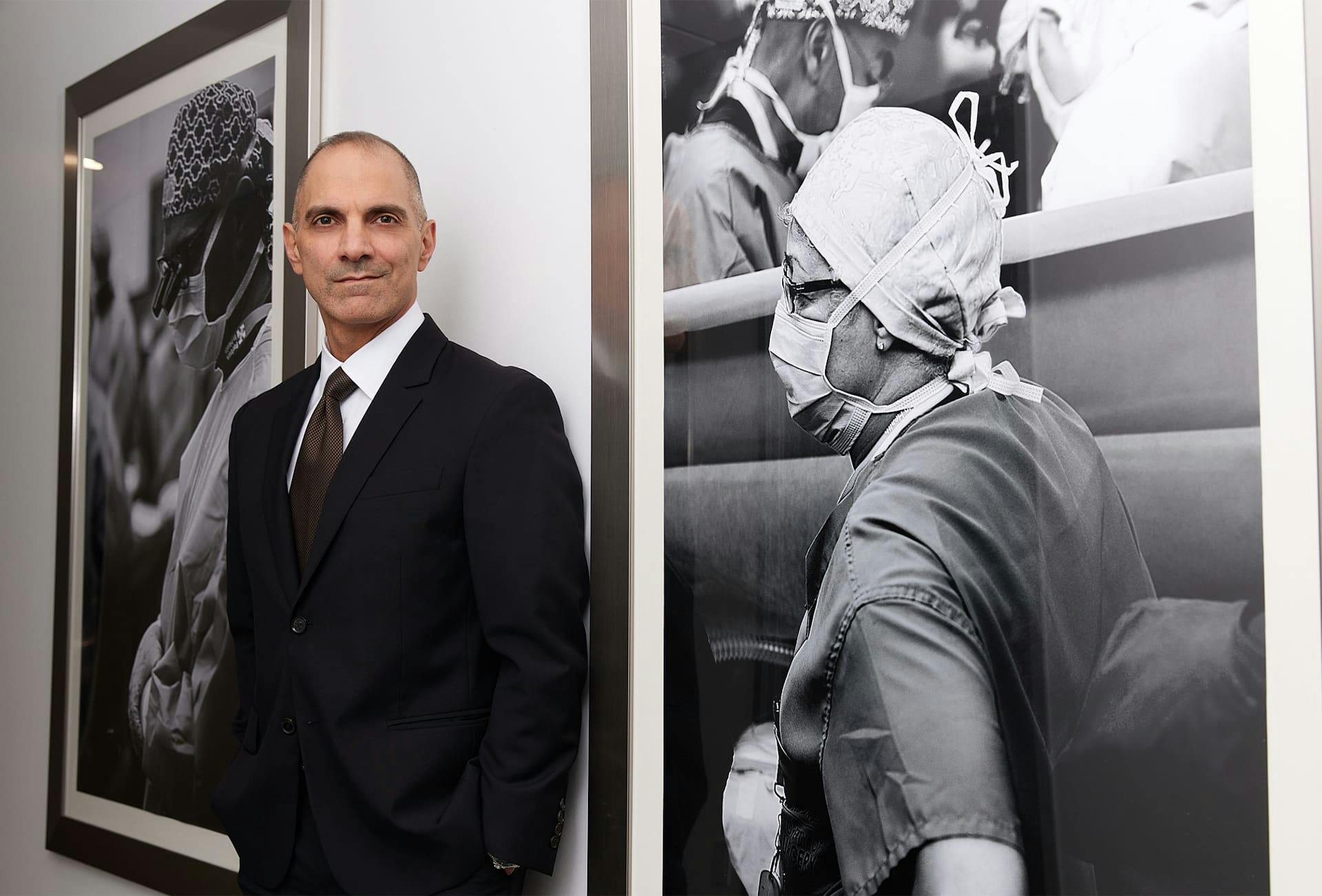 Dr. Panossian standing next to pictures on wall in suit