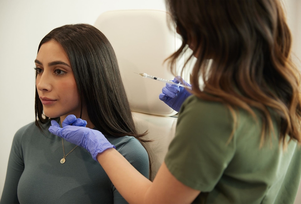 nurse holding syringe while touching patients bottom chin