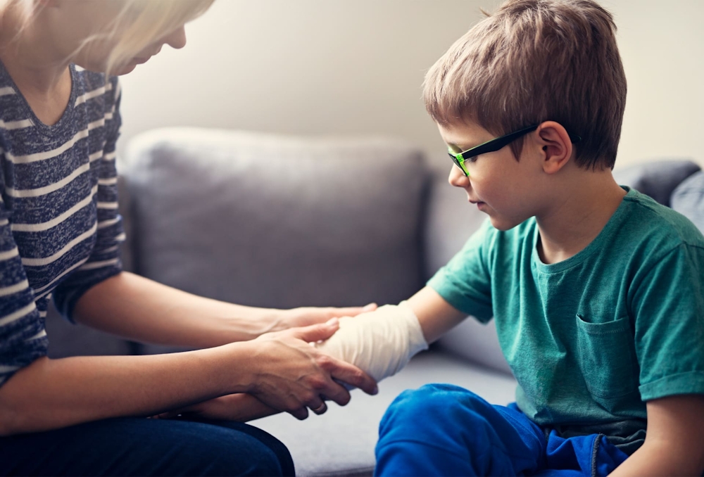 mother wrapping child's arm in bandage