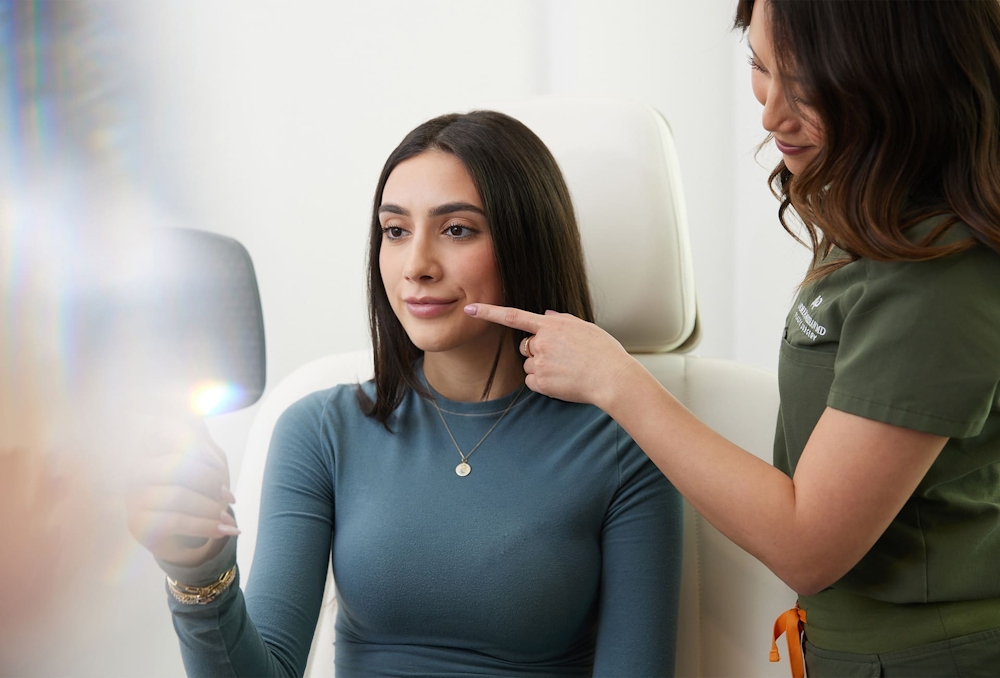 patient holding handheld mirror with nurse pointing at patient's lips