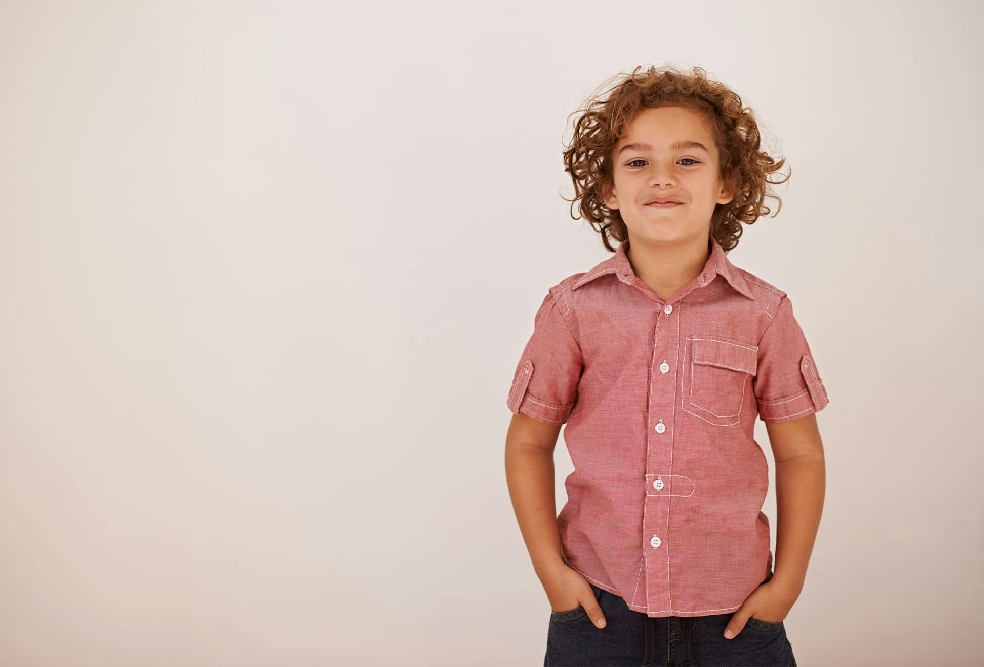 little boy with hands in pocket smiling