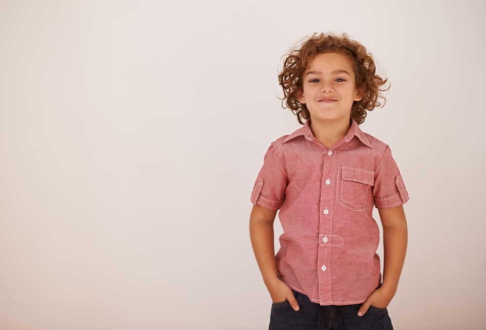 little boy with hands in pocket smiling